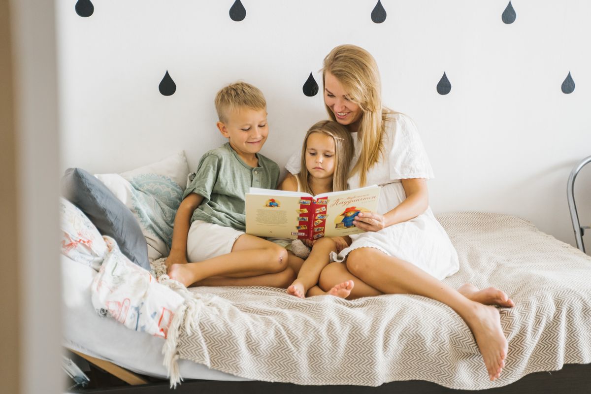 A young mother sharing a picture book with her two children